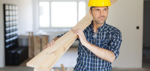 Manley construction worker holding wood planks